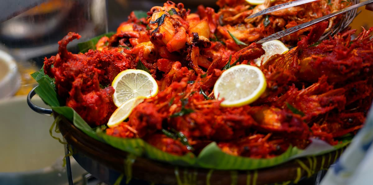 A large tray of spiced fried chicken with curry leaves and lemon