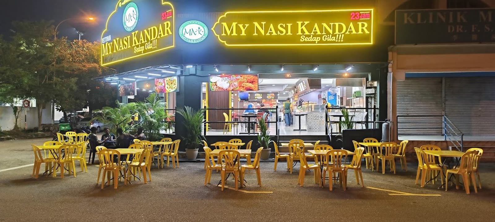 My Nasi Kandar at night, neon sign reading Sedap Gila above open-air seating